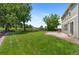 Expansive backyard with lush green grass, mature trees, and a charming swing set at 201 Shenandoah Way, Brighton, CO 80603