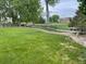 Lovely backyard featuring a green lawn and bordering a common area with mature trees and well-maintained grass at 201 Shenandoah Way, Brighton, CO 80603