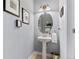 Charming powder room featuring a pedestal sink, oval mirror, and decorative wall art at 201 Shenandoah Way, Brighton, CO 80603