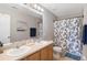 Bright bathroom featuring double sinks, large mirror, and a floral shower curtain at 201 Shenandoah Way, Brighton, CO 80603