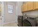Functional laundry room with modern washer and dryer units, storage cabinets, and a window at 201 Shenandoah Way, Brighton, CO 80603