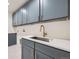 Bright laundry room with gray cabinets, white countertops, and a stainless steel sink at 6144 S Fulton St, Englewood, CO 80111