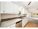 Updated kitchen with white cabinets, stainless dishwasher, and tile backsplash offers access to living room at 396 S Troy St, Aurora, CO 80012