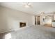 Open-concept living room features neutral carpet, fireplace, ceiling fan, and view into kitchen at 396 S Troy St, Aurora, CO 80012