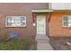Up-close exterior shot of a brick home featuring a secure screen door and covered porch at 9044 E Nassau Ave, Denver, CO 80237