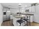 Updated kitchen with white cabinets, island with bar seating, stainless steel appliances, and wood floors at 9044 E Nassau Ave, Denver, CO 80237