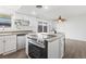 Bright kitchen with stainless steel appliances, white cabinetry, and a modern island cooktop at 9044 E Nassau Ave, Denver, CO 80237
