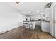 Open kitchen with an island, bar seating, white cabinetry, wood floors, and stainless steel appliances at 9044 E Nassau Ave, Denver, CO 80237