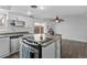 Bright kitchen features white cabinets, stainless steel appliances, an island with seating, and a ceiling fan at 9044 E Nassau Ave, Denver, CO 80237