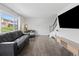 Bright living room with hardwood floors, a large window, and a modern television setup above a stylish cabinet at 9044 E Nassau Ave, Denver, CO 80237