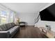 Open-concept living room featuring dark wood floors, neutral walls, a large TV, and comfortable seating at 9044 E Nassau Ave, Denver, CO 80237