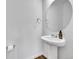 Stylish powder room featuring a pedestal sink, round mirror, and modern fixtures, creating a clean and elegant space at 210 S Old Hammer Ct, Aurora, CO 80018