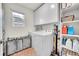 Functional laundry room with white washer and dryer, overhead cabinets, storage shelves, and ample space for organization at 210 S Old Hammer Ct, Aurora, CO 80018