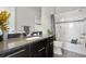 Modern bathroom featuring dark vanity, black granite countertop, soaking tub, and white tile with mosaic accent at 9154 E 37Th Ave, Denver, CO 80238