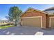 Attached two-car garage with stone facade and concrete driveway, next to a tree and a view at 7511 S Sicily Way, Aurora, CO 80016