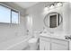 Bright bathroom features a shower-tub combination with elegant white subway tile surround and a round mirror at 807 Mobile St, Aurora, CO 80011