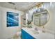 Bright bathroom with blue vanity, gold fixtures, decorative mirror, and stylish accessories at 4142 S Deframe Ct, Morrison, CO 80465