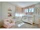 Bright Bedroom with a white crib, soft chair, decorative shelves, and charming decor at 4142 S Deframe Ct, Morrison, CO 80465