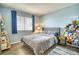 Inviting bedroom featuring a comfortable bed, wood floors, and a window with blue curtains at 4142 S Deframe Ct, Morrison, CO 80465