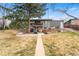 Large backyard view showcasing the home, patio area, and landscaping under a mature tree at 6445 Balsam St, Arvada, CO 80004