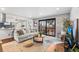 Bright living room with large slider, brick accent wall, and an open floorplan to the kitchen with hardwood floors at 6445 Balsam St, Arvada, CO 80004