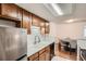 Kitchen with stainless steel appliances, wooden cabinets, and a view of the dining area at 8225 Fairmount Dr # 104, Denver, CO 80247