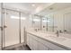 Bright bathroom featuring double sinks, white cabinetry, large mirror, and tiled shower with glass door at 1290 S Algonquian St, Aurora, CO 80018