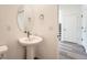 Neutral powder room featuring a pedestal sink with modern fixtures, a large mirror, and access to the staircase at 1290 S Algonquian St, Aurora, CO 80018