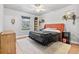 Cozy bedroom with a orange upholstered headboard, plush carpet, and natural light streaming through the window at 6324 Winona St, Arvada, CO 80003