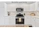 Modern kitchen with white cabinets, stainless steel appliances, and elegant backsplash at 6324 Winona St, Arvada, CO 80003