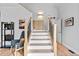 Entryway featuring a staircase with wooden banister, white risers, wooden floors, and accent furniture at 6324 Winona St, Arvada, CO 80003