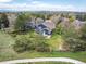 Expansive aerial view showcases lush surroundings, mature trees, and a neighborhood park at 18 Brixham Ct, Castle Pines, CO 80108