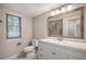 Bright bathroom featuring a white vanity with a decorative mirror and window at 18 Brixham Ct, Castle Pines, CO 80108