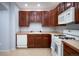Modern kitchen with wood cabinets, white appliances, and tile floor at 12826 W Brittany Dr, Littleton, CO 80127