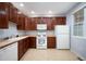 Galley kitchen with wood cabinets, white appliances, and tile floor at 12826 W Brittany Dr, Littleton, CO 80127