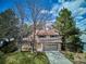 Exterior elevation with two-car garage and mature trees on a sunny day at 13183 Spica Dr, Lone Tree, CO 80124