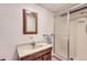This is a bathroom with a stand-up shower, single-sink vanity, and a wood-trimmed mirror at 13940 E Linvale Pl, Aurora, CO 80014