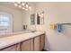 This well-lit bathroom features wood cabinets, a large mirror, and neutral countertops at 13940 E Linvale Pl, Aurora, CO 80014