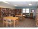 Community library with well-stocked bookshelves, tables, chairs, and a window for natural light at 13940 E Linvale Pl, Aurora, CO 80014