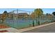 Fenced tennis court with green and blue surfaces, surrounded by trees and landscaping at 13940 E Linvale Pl, Aurora, CO 80014