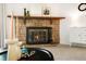 Close-up of the stone fireplace with mantel decor, brass fireplace tools, and a modern white cabinet at 3452 S Eagle St # 101, Aurora, CO 80014