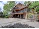 Spacious home with a multi-level deck, a stone foundation, a two-car garage, and beautiful mature trees at 34127 Cactus Dr, Evergreen, CO 80439