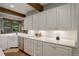 Kitchen with white cabinets, countertops, and a farmhouse sink illuminated by under-cabinet lighting at 34127 Cactus Dr, Evergreen, CO 80439