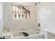 Bright bathroom features a soaking tub beneath a window and white tiled walls at 764 S Corona St, Denver, CO 80209