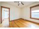 Bright bedroom with wood floors, ceiling fan, and wooden trim around the window and doorway at 3024 W Denver Pl, Denver, CO 80211