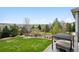 Spacious backyard with a large lawn, mature trees, and a covered hot tub area at 5310 Craftsman Dr, Parker, CO 80134