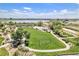 Aerial view showcases community park amenities: a lake, basketball court, soccer field, and walking paths at 9530 E 113Th Ave, Commerce City, CO 80640