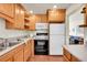 A view of the kitchen with wood cabinets and black appliances with a glimpse into the living room at 755 S Clay St, Denver, CO 80219