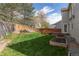 Well-maintained backyard with green lawn, wooden fence, garden beds, and a cozy deck at 9525 W Victoria Dr, Littleton, CO 80128