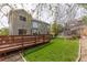 Charming backyard view featuring a wooden deck, lush green lawn, and landscaped garden beds at 9525 W Victoria Dr, Littleton, CO 80128